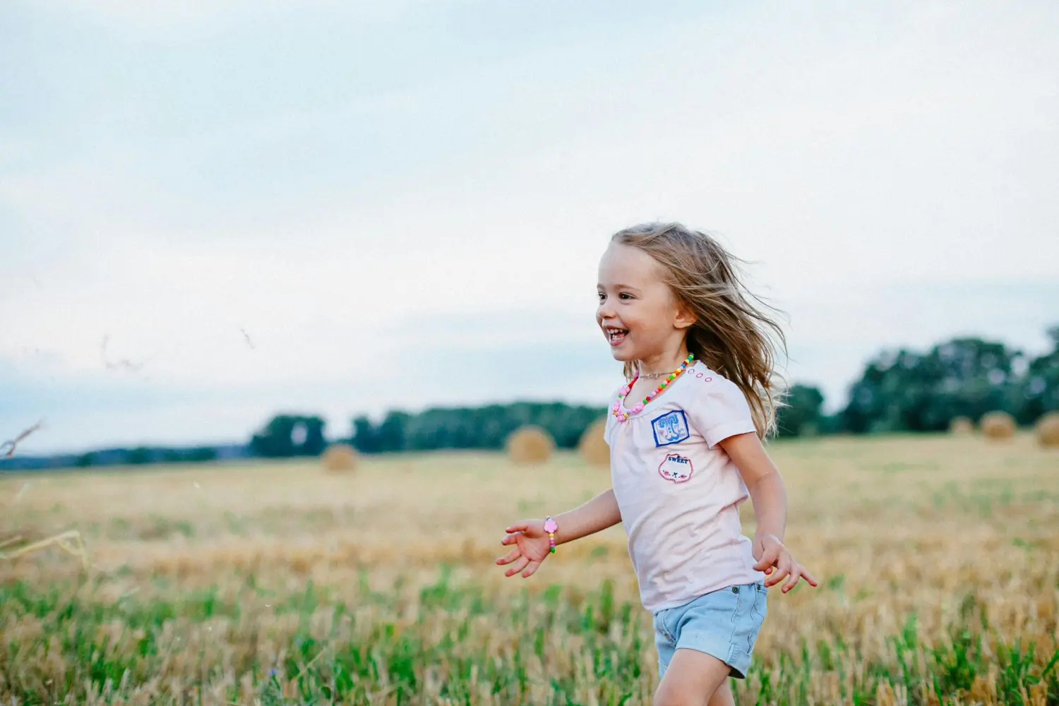 Ergotherapie Obstallee, ein kleines Mädchen rennt im freien Feld