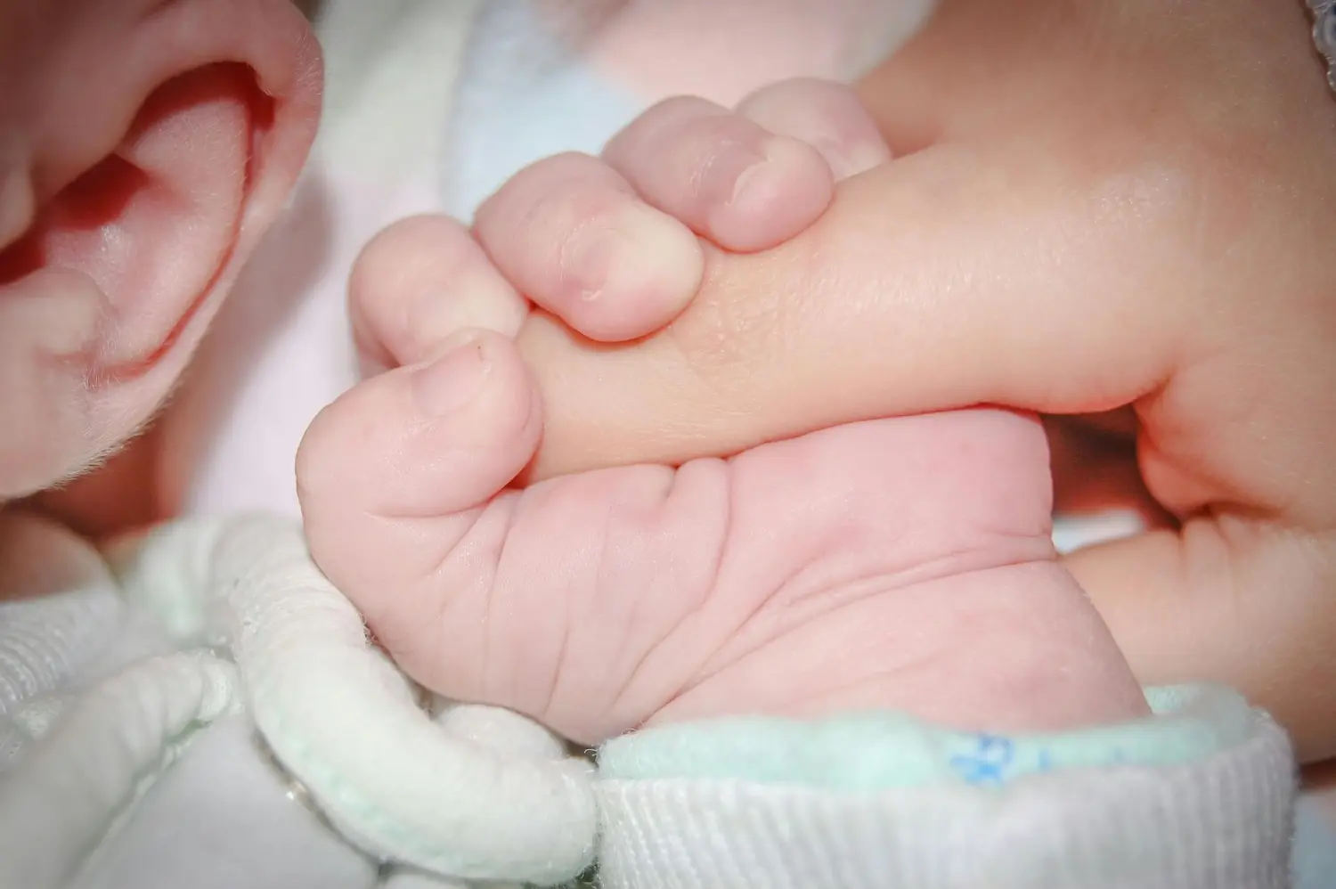 Ergotherapie Obstallee, die Hand des Babys hält den Finger der Mutter