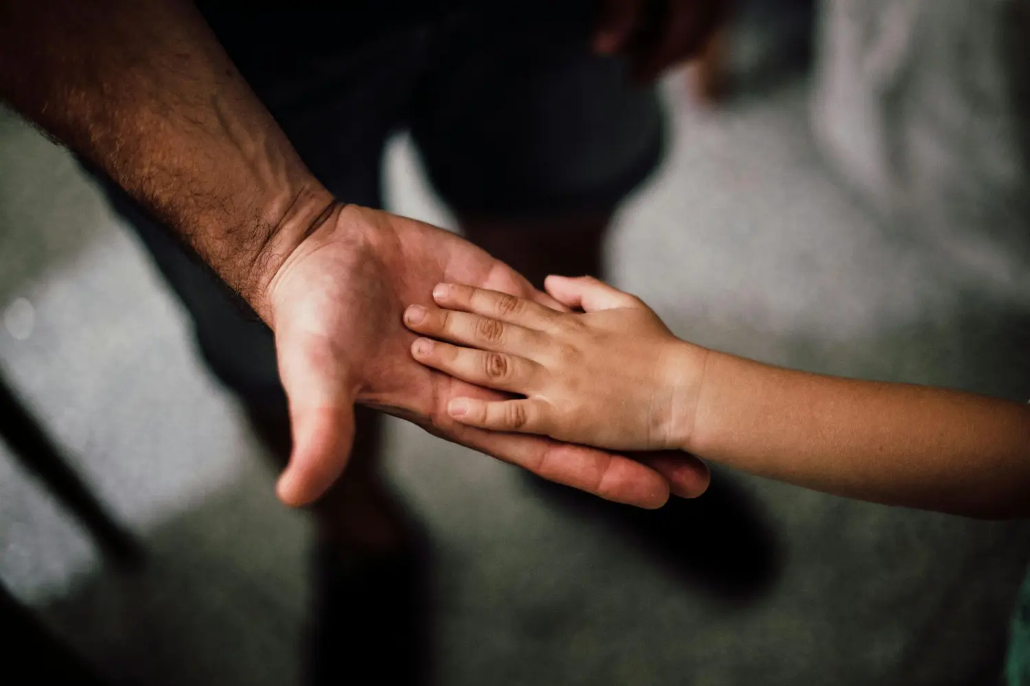 Ergotherapie Obstallee, die Hand eines Kindes in der Hand seiner Eltern